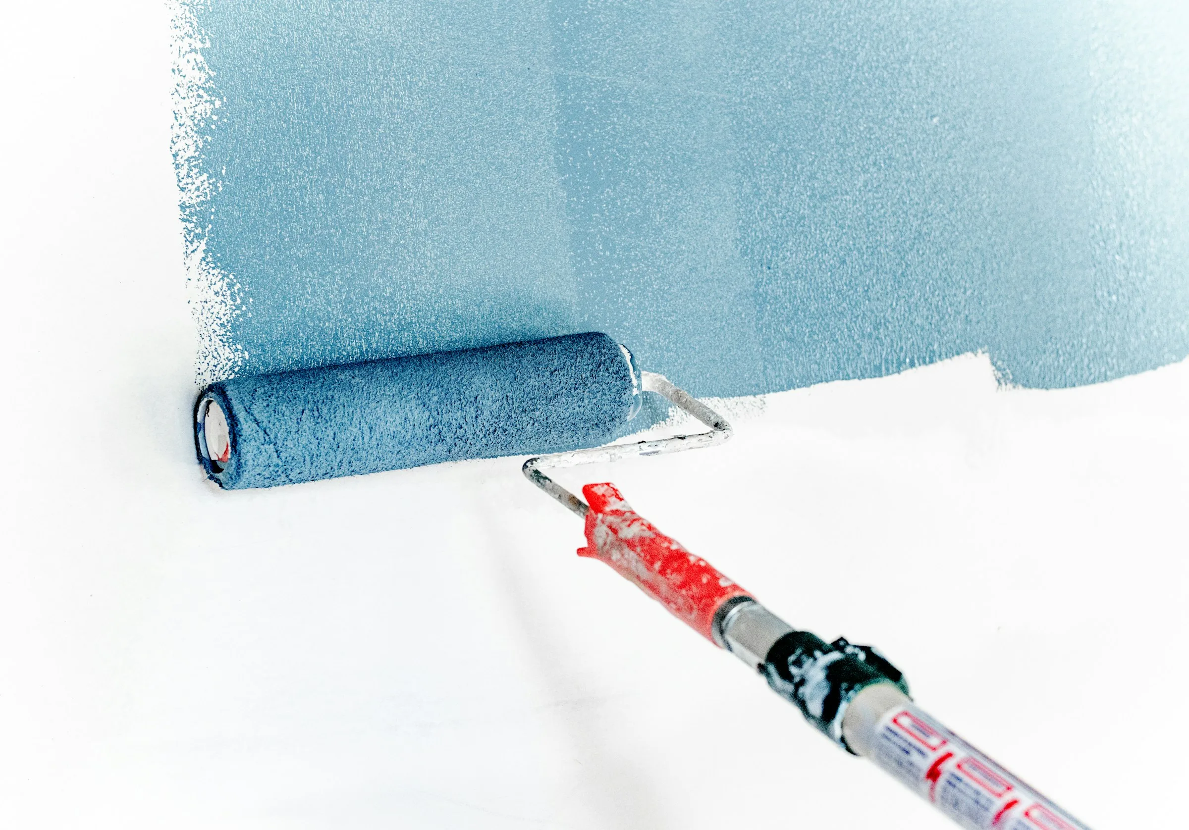 Blaue Beschichtung wird mit einer Rolle auf eine Fläche aufgetragen, Symbolbild